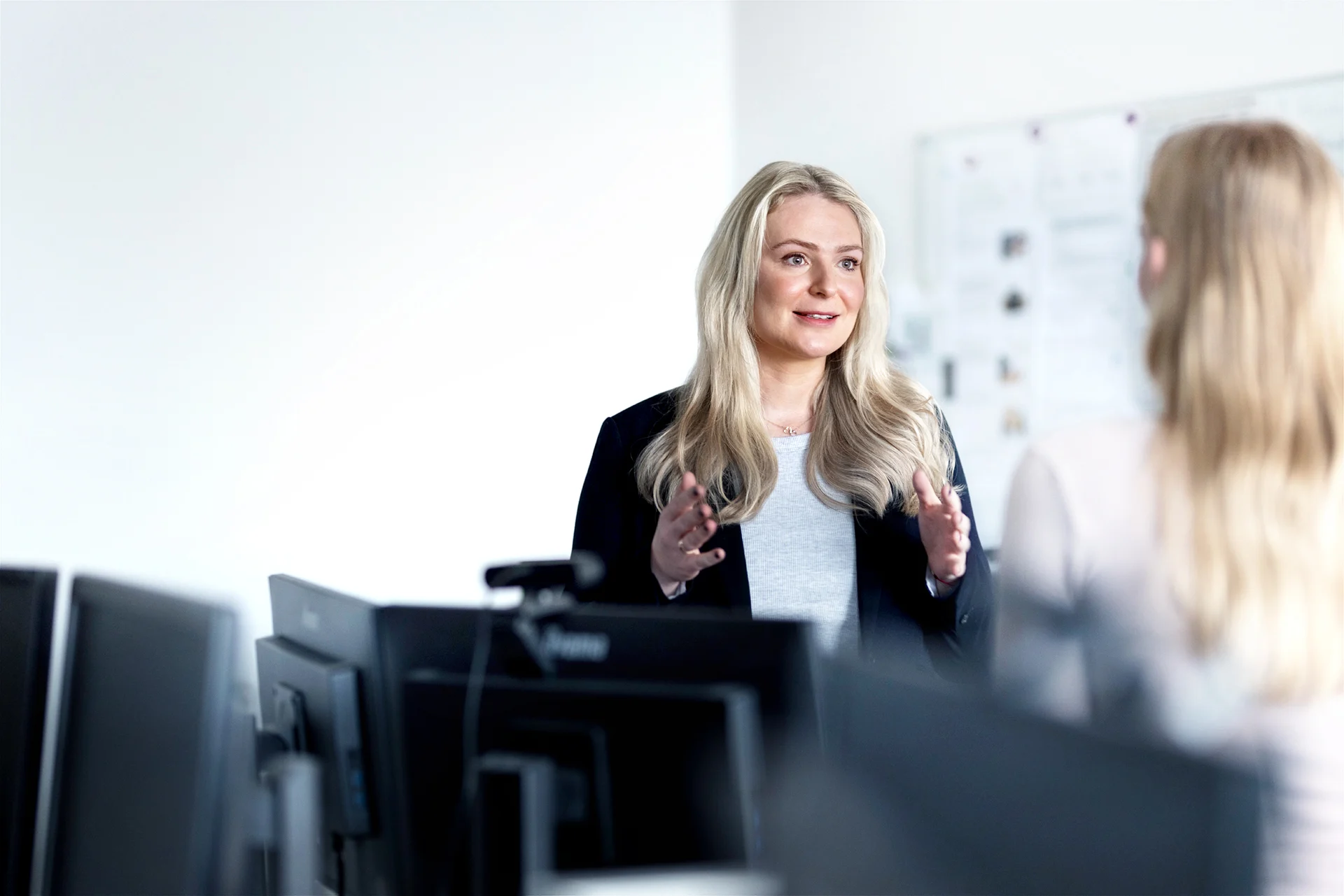 Teaserbild mit zwei sich unterhaltenden Mitarbeiterinnen im Büro vor weißer Wand