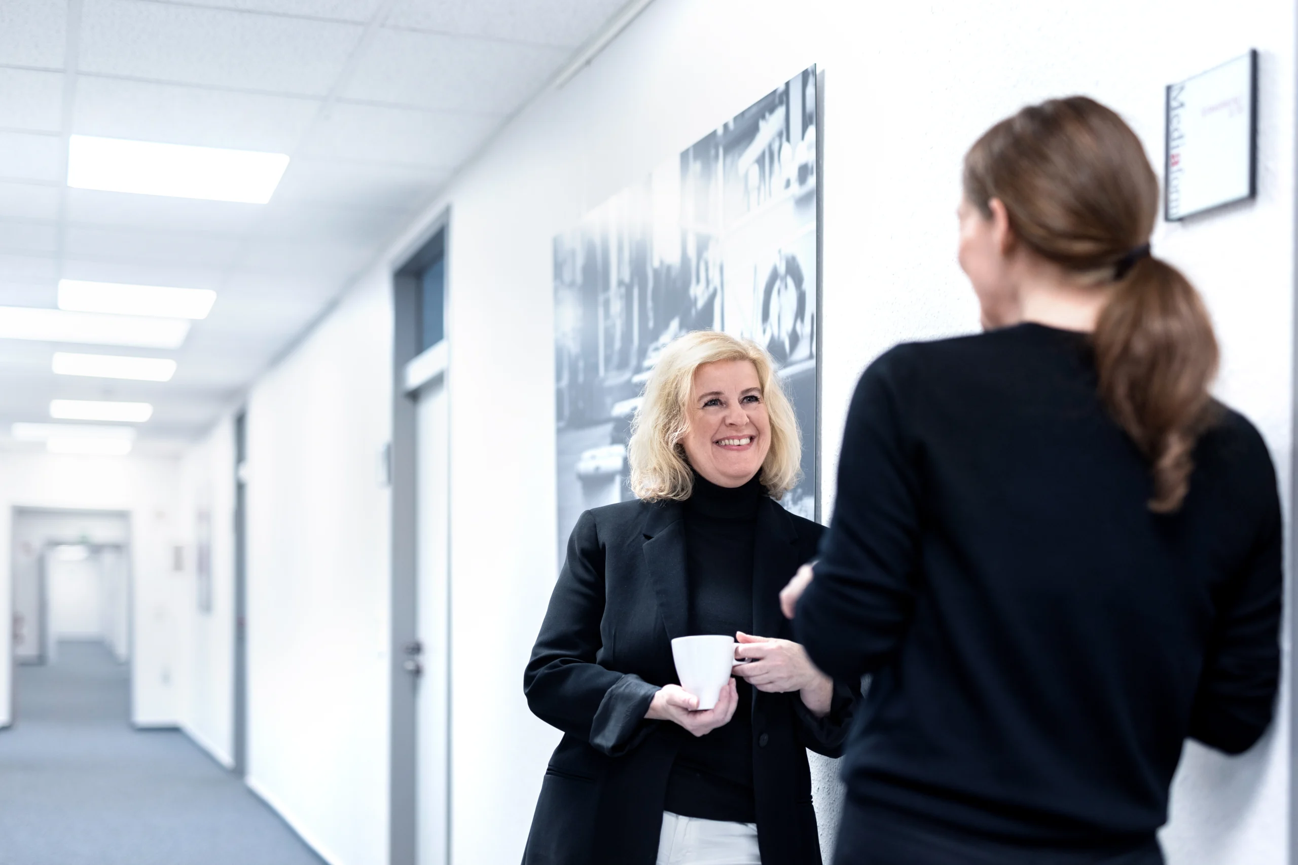 Zwei Mediaform Mitarbeiterinnen im Gespräch auf dem Büroflur.