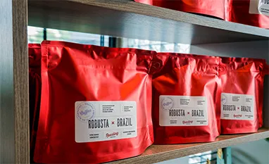Red coffee bags with labels on the shelf: Barista Brazil