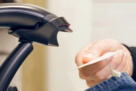 Warenetikett eines Kleidungsstückes wird im Geschäft mit einem schwarzen Barcodescanner erfasst